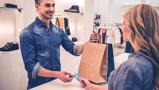 Shopper hands the merchant her privilege card created with the Badgy printer